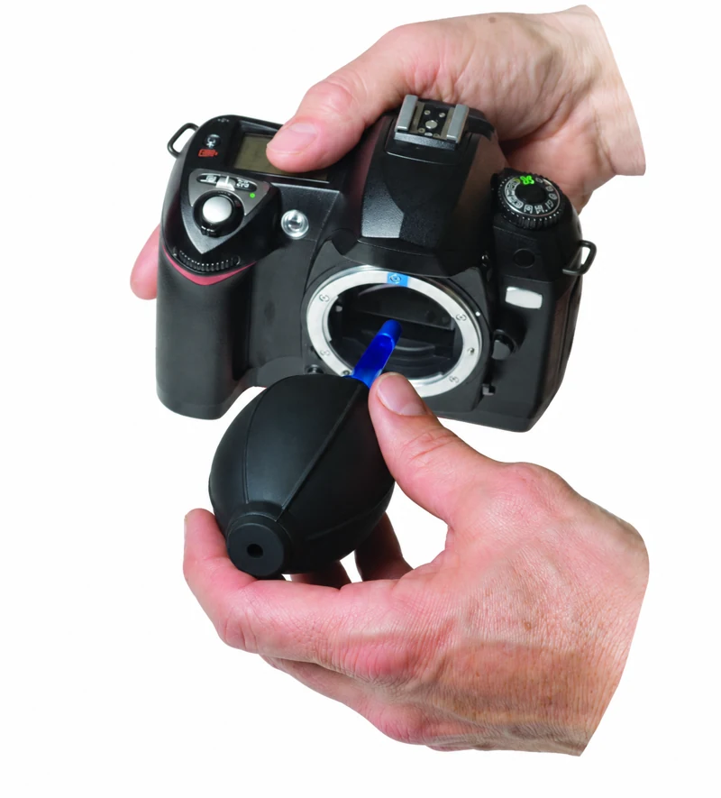 Hands using the LensPen Hurricane Blower to blow dust from an open DSLR sensor chamber